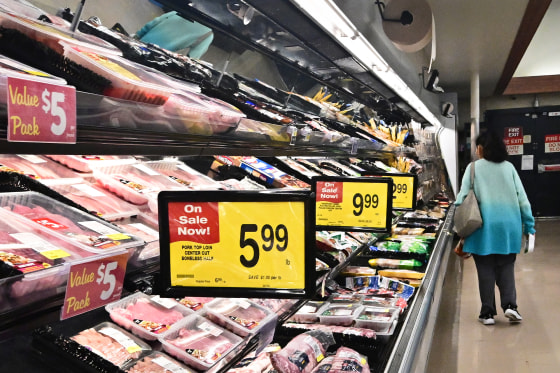 A person walks near the meat aisle a grocery store