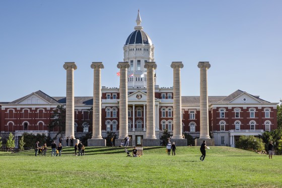 A wide view of the University of Missouri campus, students walk on the lawn