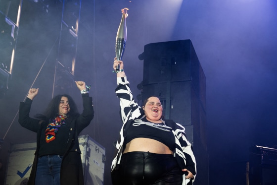 French DJ Barbara Butch (R) holds the paralympic flame flanked by French-Iranian writer Marjane Satrapi during the 20th edition of the Rock en Seine music festival, in Saint-Cloud, outside Paris, on August 25, 2024. 