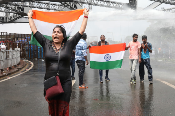 A protester holds a flag as police use a water cannon