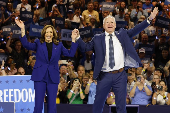 Kamala Harris and Tim Walz acknowledging the crowd at a campaign rally.