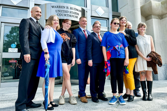 Parker Tirrell, third from left, and Iris Turmelle, sixth from left, pose with their families and attorneys outside of a courthouse