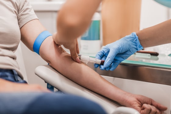 Close-up Of Doctor Taking Blood Sample From Patient's Arm in Hospital for Medical Testing.