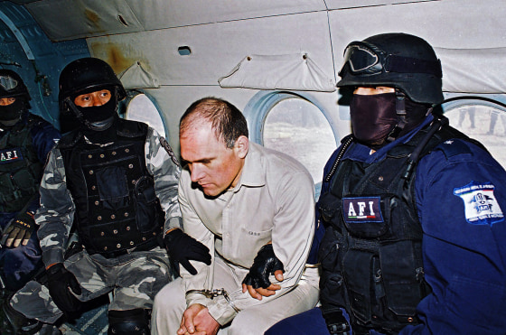 Osiel Cárdenas Guillén sitting in a plane in handcuffs between agents of Mexico's Federal Agency of Investigations