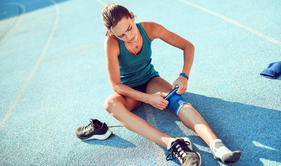 Female Bandaging Her Knee Before Running On Track.