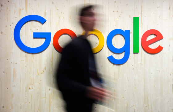 Trade fair visitors walk past a Google logo at the Google stand at Hannover Messe 2024.