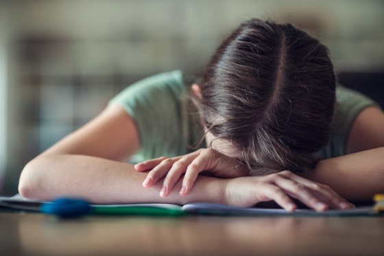 Teenage girl with head in hands, fed up with school homework