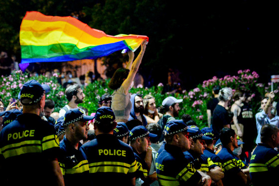 A participant holds a rainbow flag next to police officers