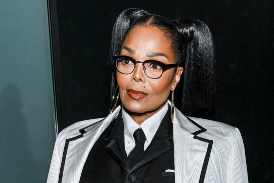 Janet Jackson looks ahead wearing glasses and a white blazer