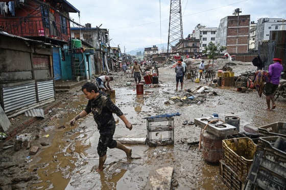 People walk through muddy streets filled with debris