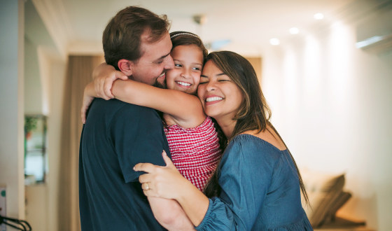 Parents and daughter cuddling in the living room.