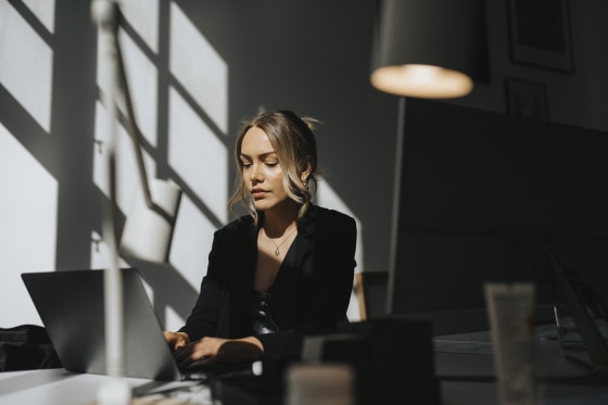 Young businesswoman working on laptop sitting at office