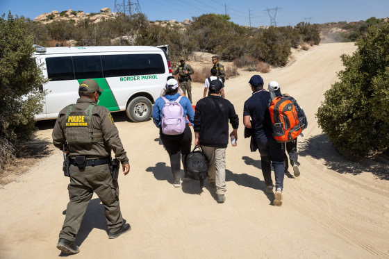 Asylum seekers walk towards a Border Patrol van