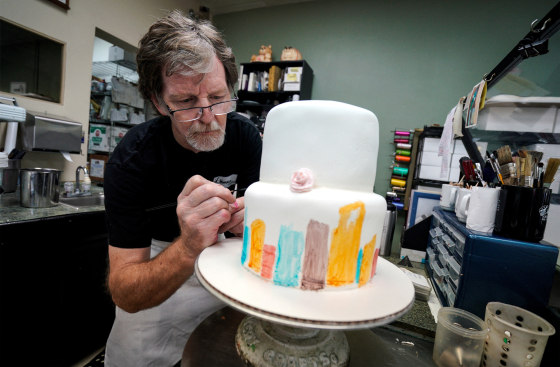 Jack Phillips decorates a white fondant cake in his shop