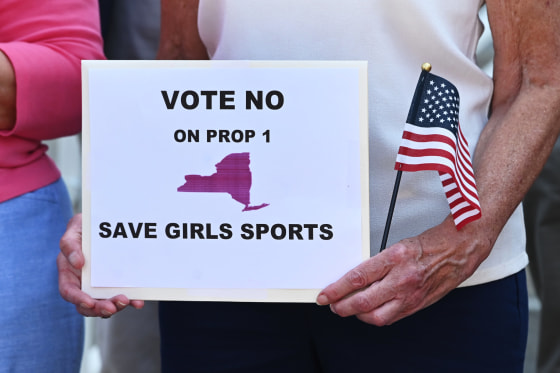 A woman holds a sign to vote no for proposition 1 