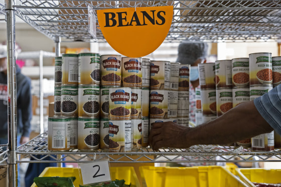 A volunteer restocks canned food on the shelves of a food bank