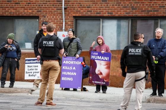 People hold anti-abortion signs outside of a clinic