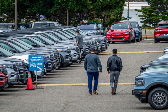 People look at cars at the dealeship.