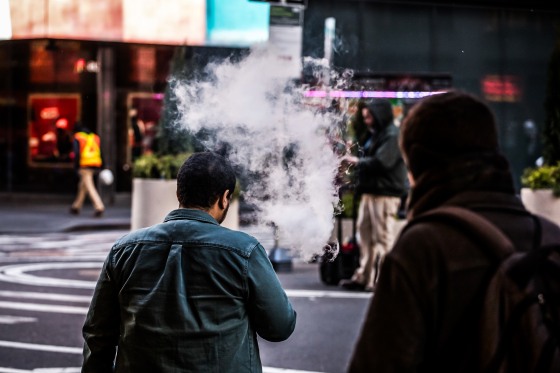 A person exhales vapor while using an electronic cigarette device