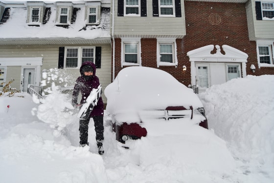 A person shovels snow from their driveway