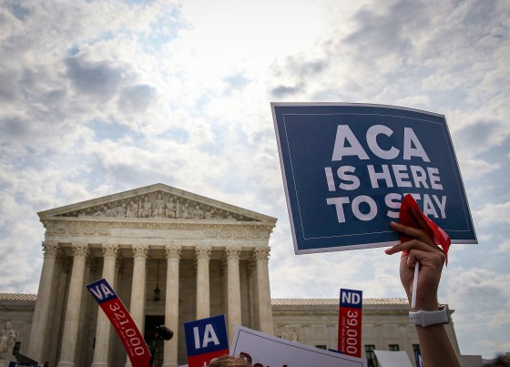 A sign is held up that reads "ACA Is Here To Stay" front of the U.S. Supreme Court.