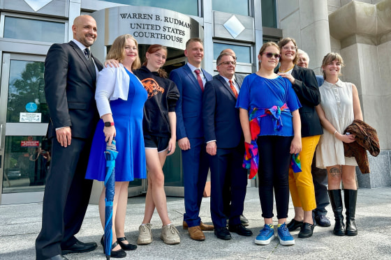 A group of people stand for a photo outside of a courthouse