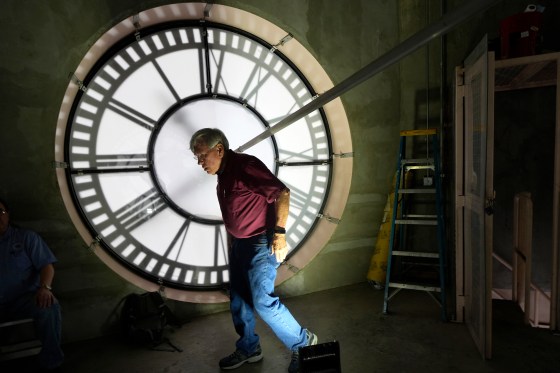 a man walking in front of a large clock