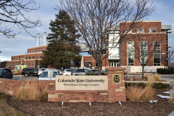 A sign for Colorado State University in front of a campus building outside