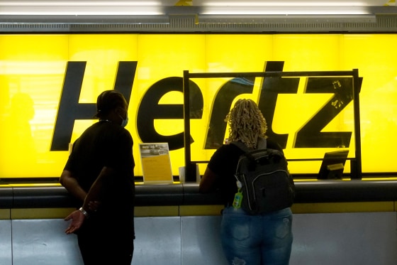 People stand at a Hertz car rental counter