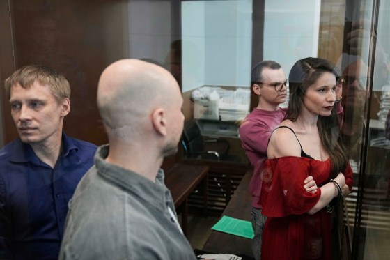Russian journalists stand in the defendants' cage.