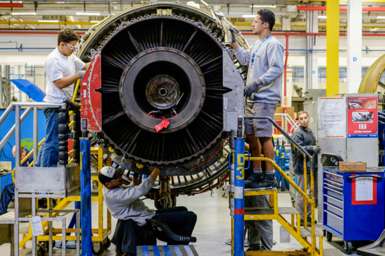 Men work with a jet engine at General Electric.