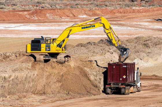 An excavator pours Uranium tailings into a container truck