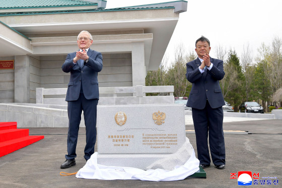 Two officials applauding at the ceremony for the construction of a bridge between North Korea and Russia