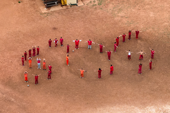 A drone view of detainees forming the letters SOS with their bodies in the courtyard