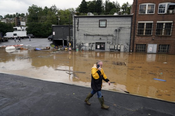 A man walks near a flooded area near the Swannanoa river