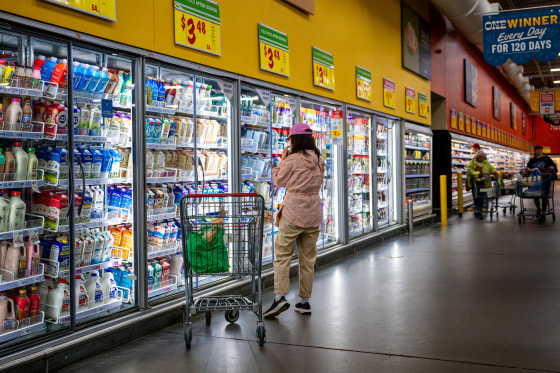 A customer browses refrigerated drinks in a grocery store.