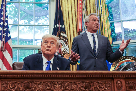 Donald Trump sits at his desk, left, in the oval office while Robert F Kennedy Jr stand behind him and speaks while gesturing