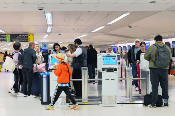 Passengers wait in line to check in for their flights 
