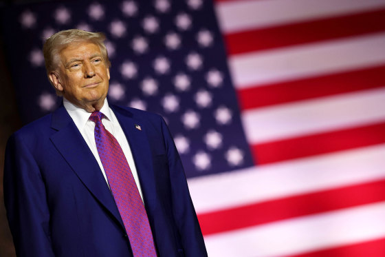 President Donald J. Trump stands on stage in front of the US flag