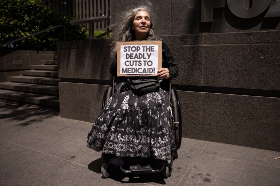 A protester holds a sign that reads "Stop the Deadly Cuts to Medicaid."