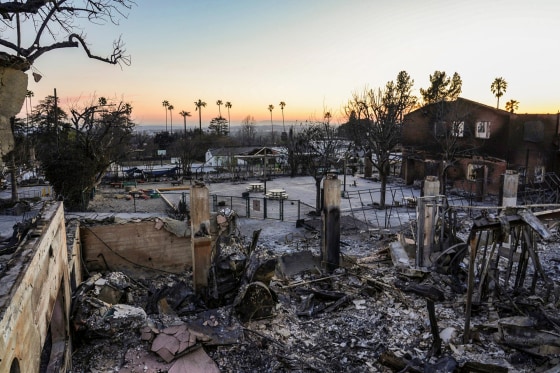 A charred house and debris is seen outside at sunset