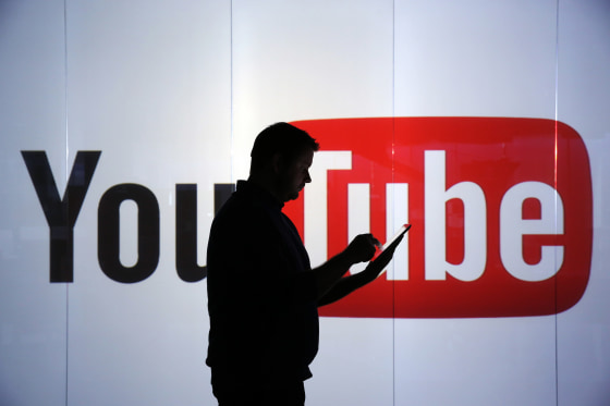 Image: A man stands in front of YouTube's logo at an office in London