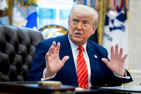 Donald Trump speaks while seated at his desk in the Oval Office
