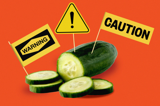 Photo illustration of cucumber with warning signs attached to it 