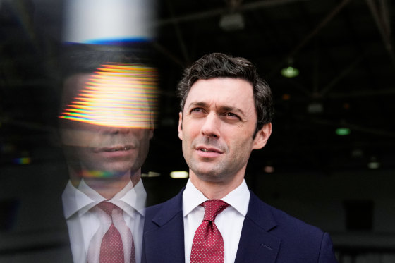 Jon Ossoff looks upwards, a reflection of himself is beside him