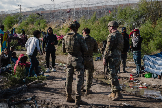 Members of the Texas National Guard walk through an encampment of migrants after they crossed the US-Mexico border through the Rio Grande in El Paso, Texas on April 2, 2024. 