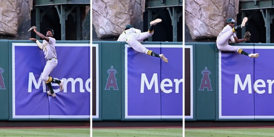 Oakland Athletics Denzel Clarke leaps over the wall to catch a fly ball at Angel Stadium in Anaheim, Calif., on Monday.
