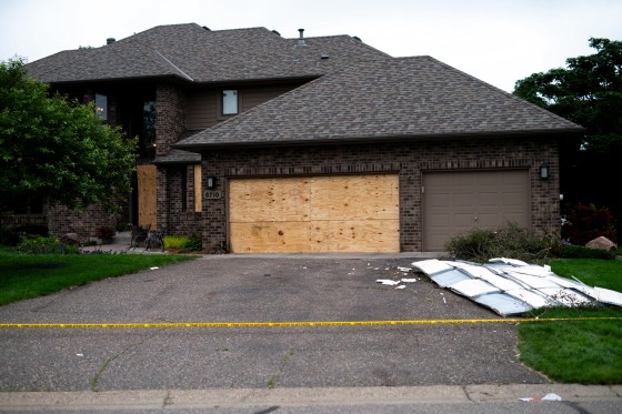 Boards cover the doors and windows outside of a home