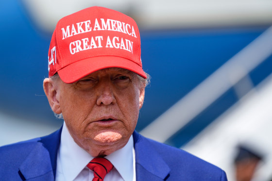 Donald Trump wears a red "Make America Great Again" hat outside