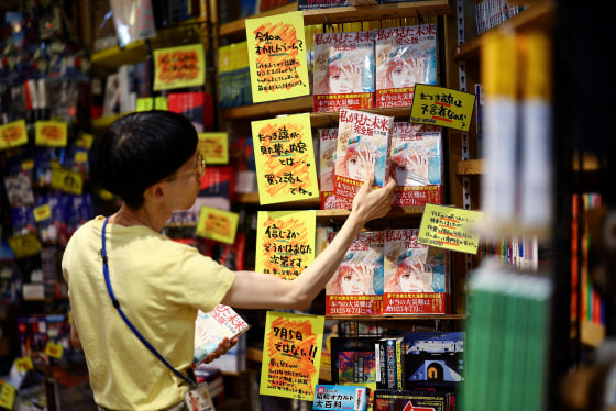 A member of staff places the comic book titled 'The Future I saw', authored by manga artist Ryo Tatsuki, on the shelf at Village Vanguard book store in Tokyo